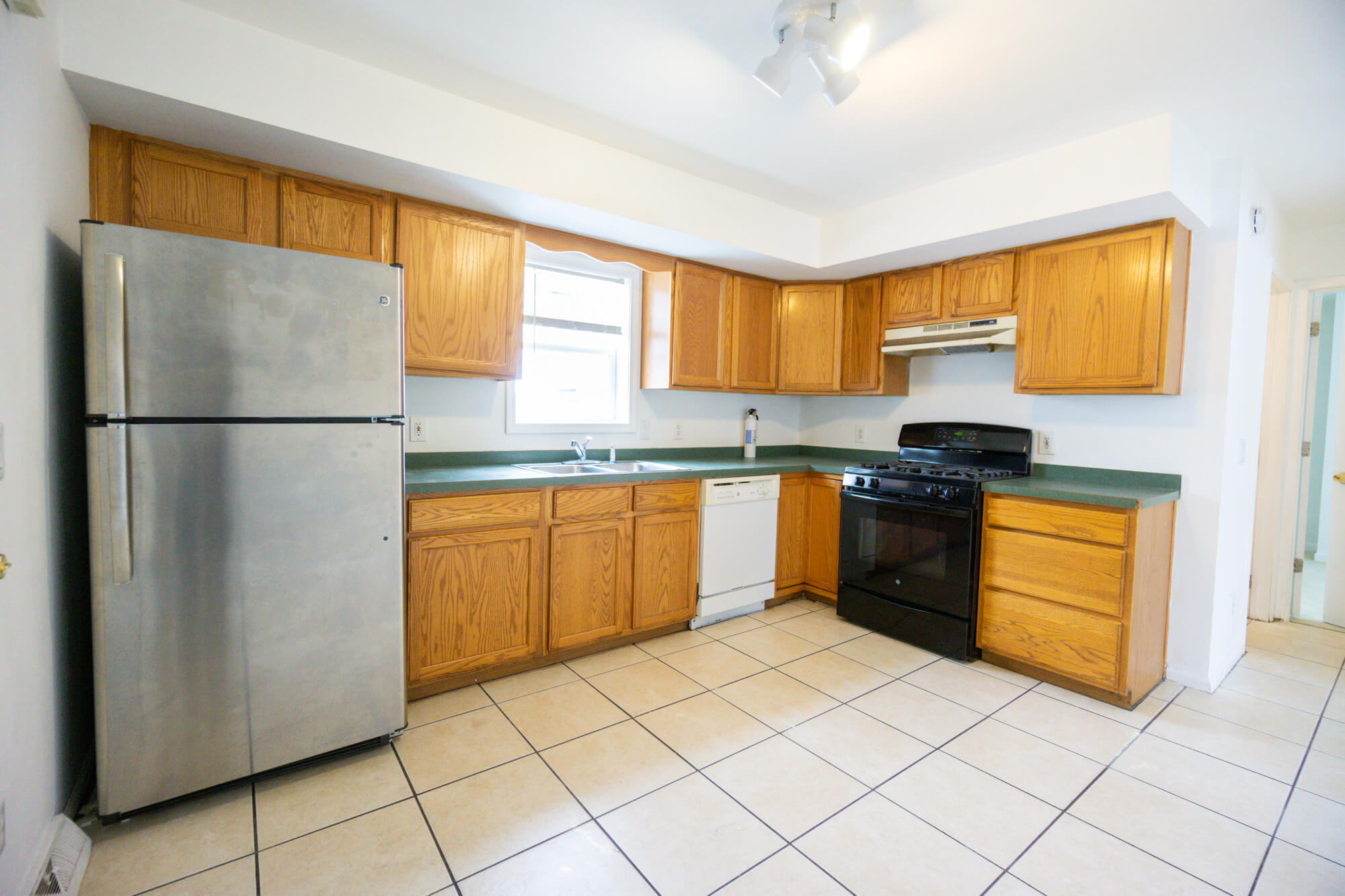 First floor kitchen with fridge, sink, dishwasher, stove, and cabinets. 